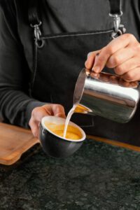Atraskite tobulo espresso paslaptis – nuo pupelių iki kremo Puodelis šviežiai paruošto espresso su auksinės spalvos kremo sluoksniu ant stalo.